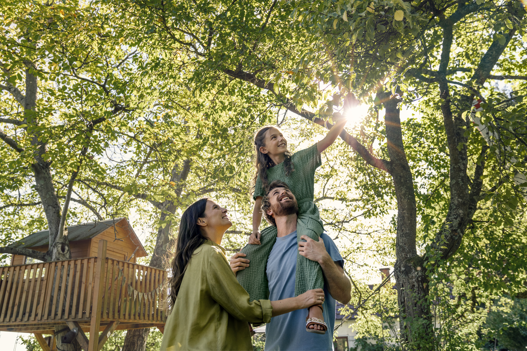 Lächelnde Familie im sonnendurchfluteten Garten.