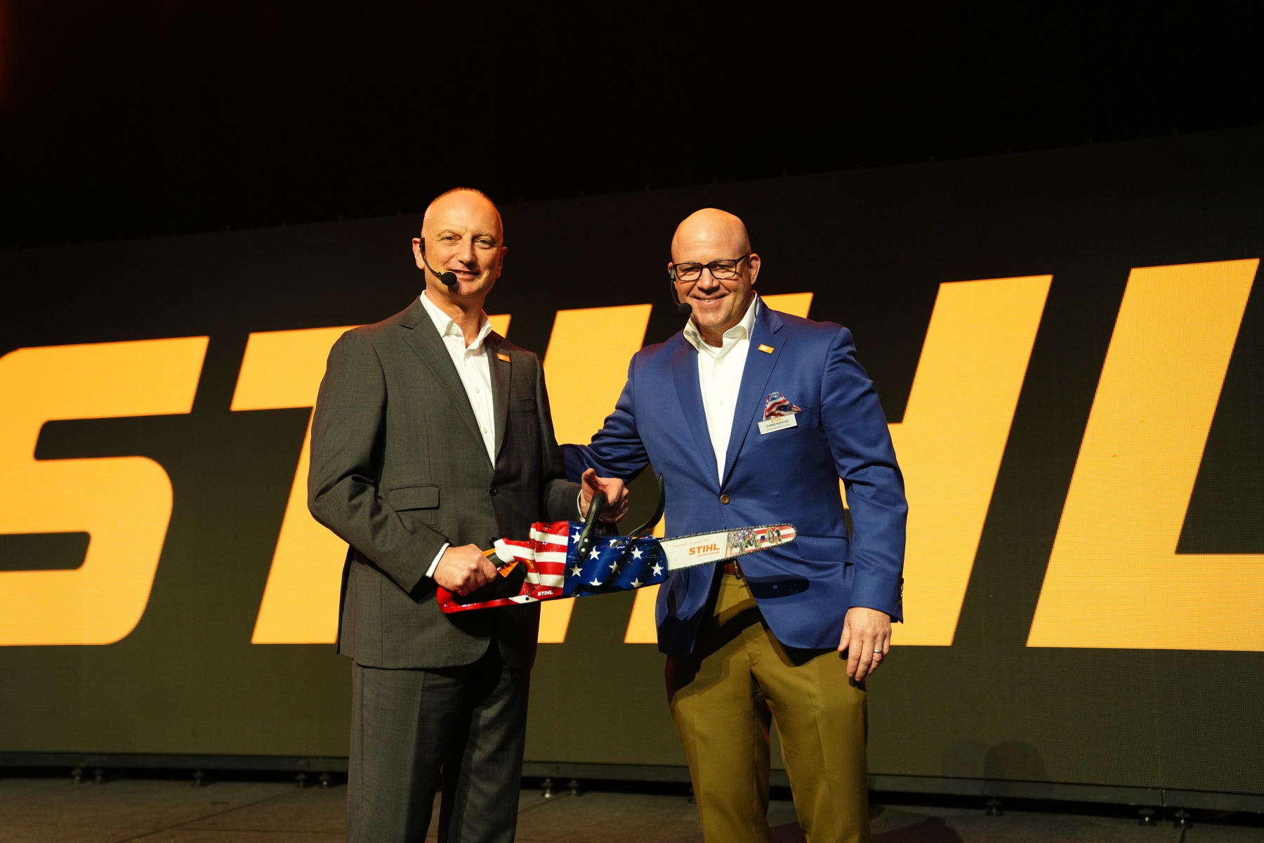 Dr. Nikolas Stihl (links) und Chris Keffer, Geschäftsführer von STIHL Inc. in den USA, präsentieren eine Jubiläumsäge mit US-Flagge.